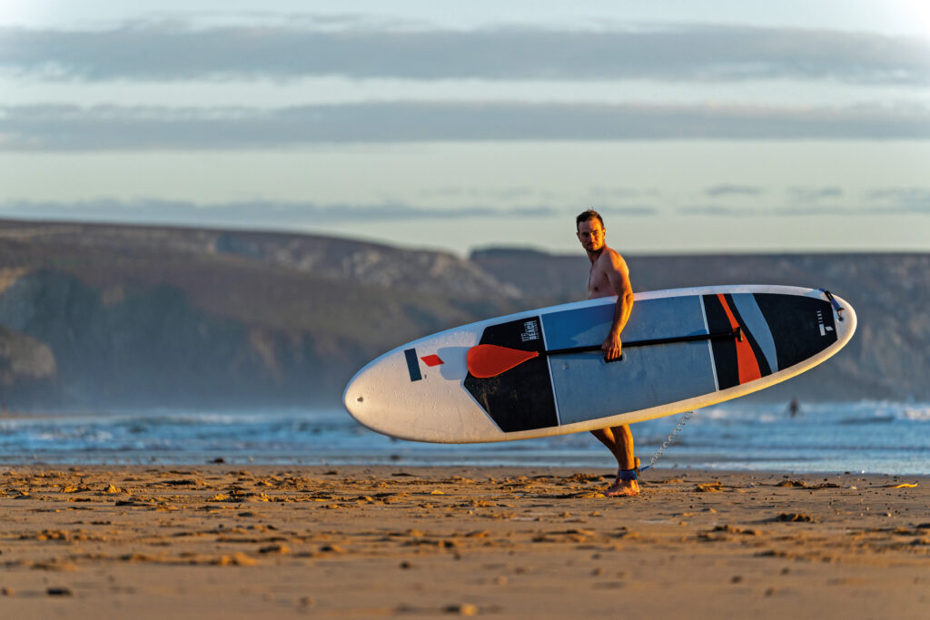 homme qui marche avec planche de paddle